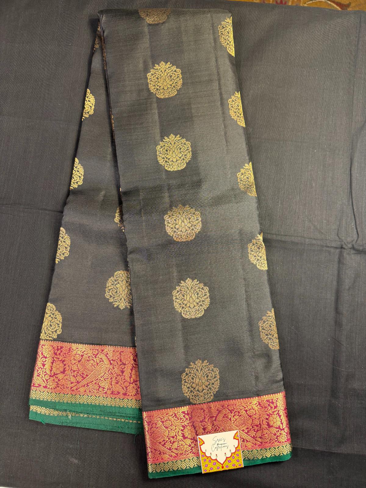 Black Pure Kanjivaram Pattu with all over butas and maroon and green border with peacocks