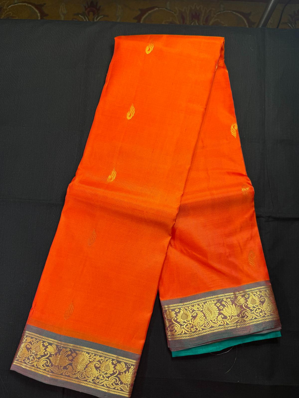 Orange pure kanjivaram pattu with all over jari butas and small border with mango and lotus flowers
