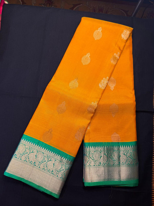 Yellow Pure Kanjivaram Pattu with peacocok butas all over, green double border with peacocks