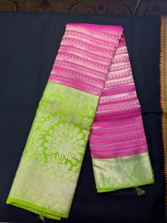 Pink pure kanjivaram pattu with all over jari lines and butas, with big green border including peacock, flowers and wheel design